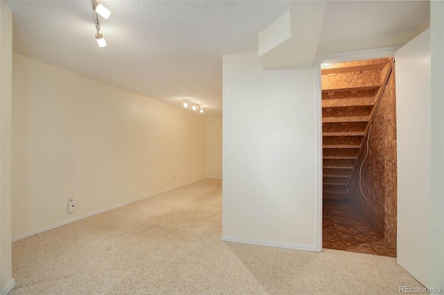 finished basement featuring rail lighting, a textured ceiling, and carpet