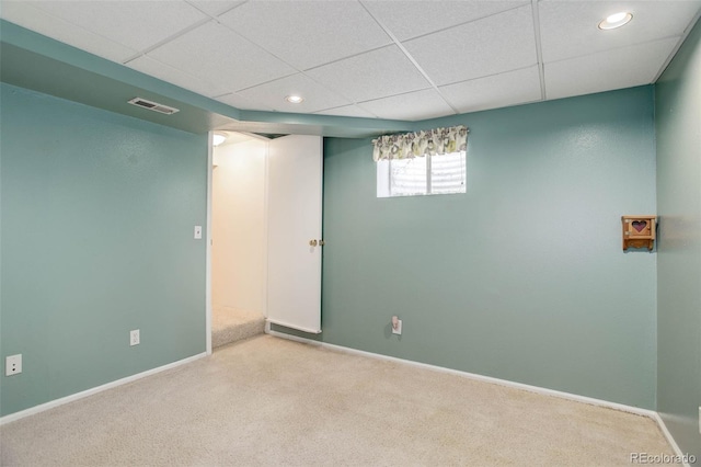 basement featuring visible vents, a drop ceiling, baseboards, and carpet floors