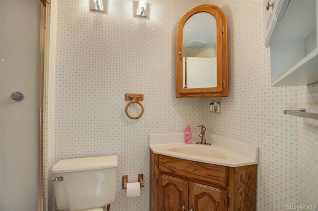 bathroom featuring wallpapered walls, toilet, and vanity