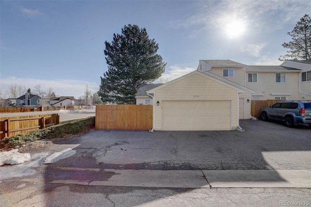 exterior space featuring an attached garage, fence, a residential view, and driveway