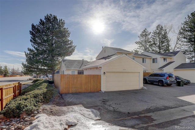 view of side of property featuring fence and a garage