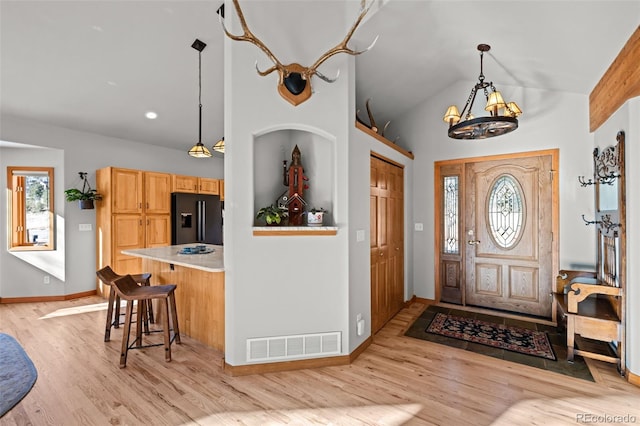 foyer featuring lofted ceiling, visible vents, light wood-style flooring, a chandelier, and baseboards