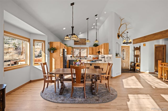 dining area with arched walkways, high vaulted ceiling, baseboards, and light wood-style floors