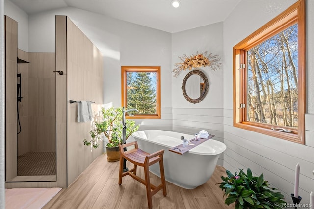 bathroom featuring a freestanding tub, wooden walls, wood finished floors, wainscoting, and a shower stall