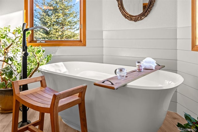 bathroom with wood walls and a soaking tub