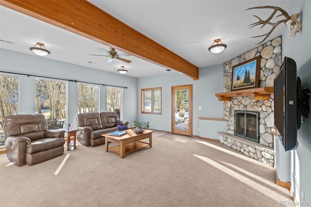 carpeted living room featuring ceiling fan, a fireplace, baseboards, and beam ceiling