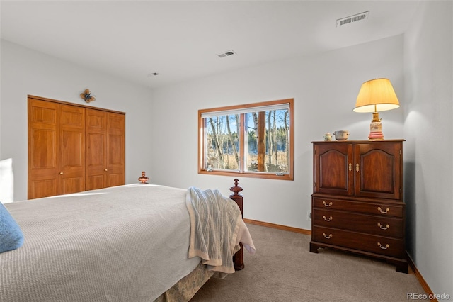 bedroom with a closet, visible vents, light carpet, and baseboards