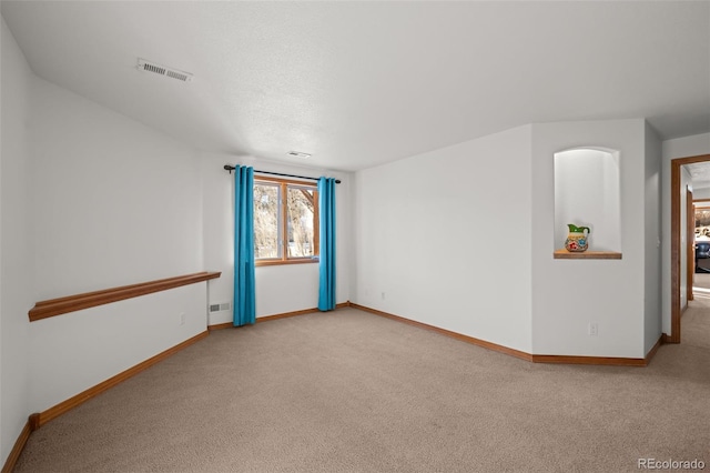 carpeted empty room with visible vents and baseboards