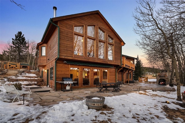 snow covered back of property with a patio area