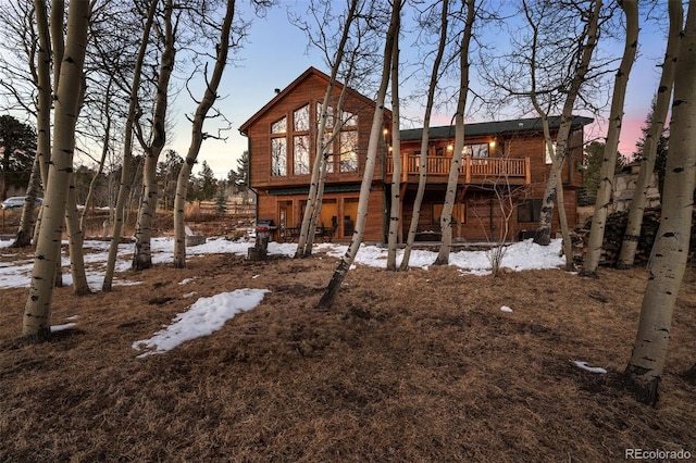 snow covered back of property featuring a wooden deck