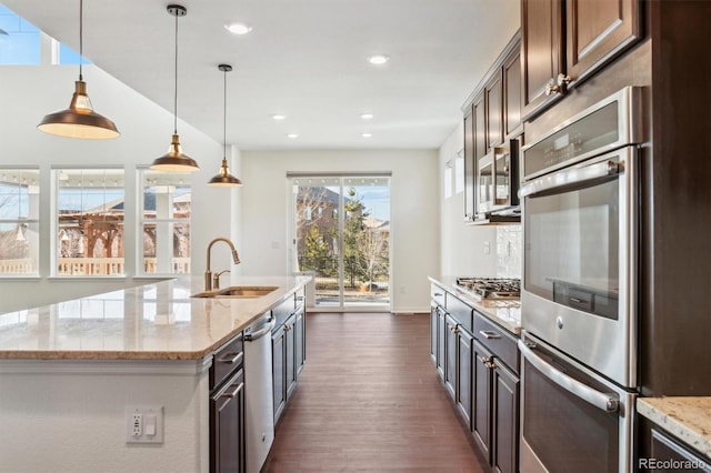 kitchen with a sink, light stone counters, dark wood-style floors, recessed lighting, and appliances with stainless steel finishes