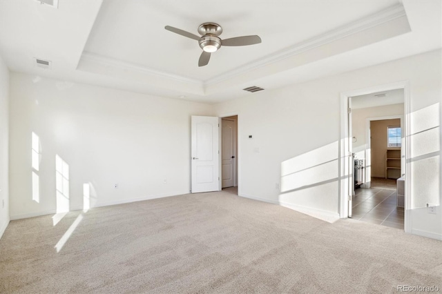 carpeted spare room featuring visible vents, baseboards, crown molding, and a tray ceiling