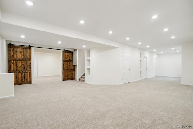 finished basement with light carpet, stairway, recessed lighting, and a barn door