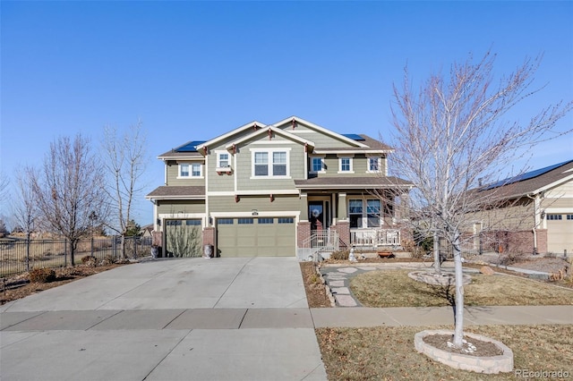 craftsman-style house with roof mounted solar panels, a porch, fence, concrete driveway, and brick siding