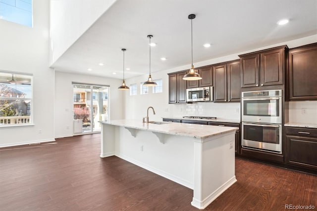 kitchen featuring dark brown cabinetry, appliances with stainless steel finishes, dark wood-type flooring, and a sink