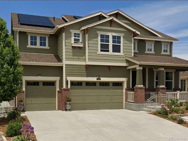 craftsman-style house featuring driveway, a porch, a garage, brick siding, and roof mounted solar panels