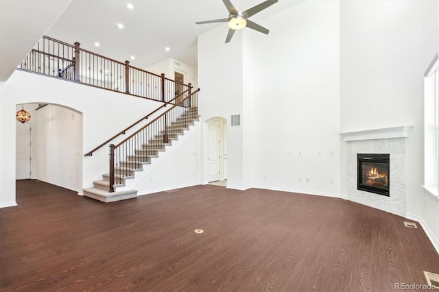 unfurnished living room with a fireplace, stairway, wood finished floors, and visible vents