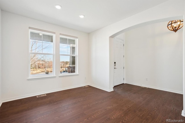 unfurnished room with visible vents, baseboards, dark wood finished floors, recessed lighting, and arched walkways