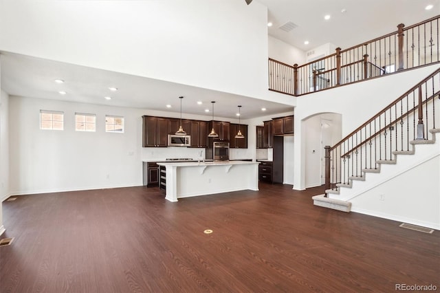 unfurnished living room featuring recessed lighting, baseboards, dark wood-type flooring, and stairs