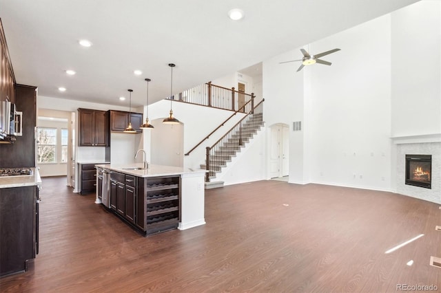 kitchen with open floor plan, dark wood-style flooring, a glass covered fireplace, and a sink