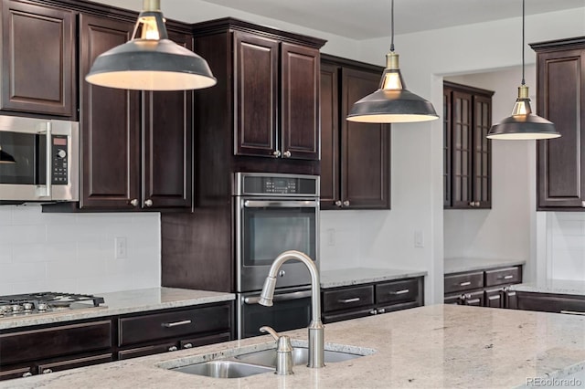 kitchen featuring a sink, light stone countertops, appliances with stainless steel finishes, and dark brown cabinets