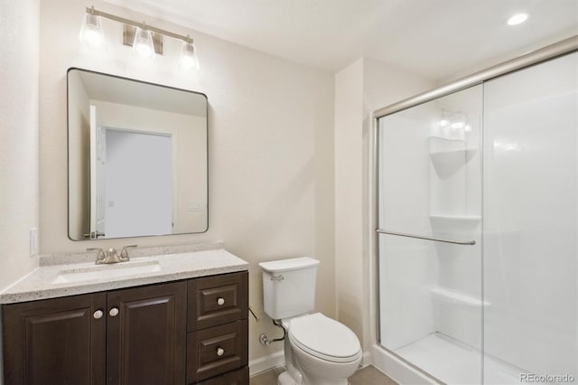 full bath featuring baseboards, toilet, a stall shower, and vanity