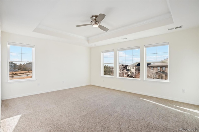 spare room with a wealth of natural light, visible vents, and a tray ceiling