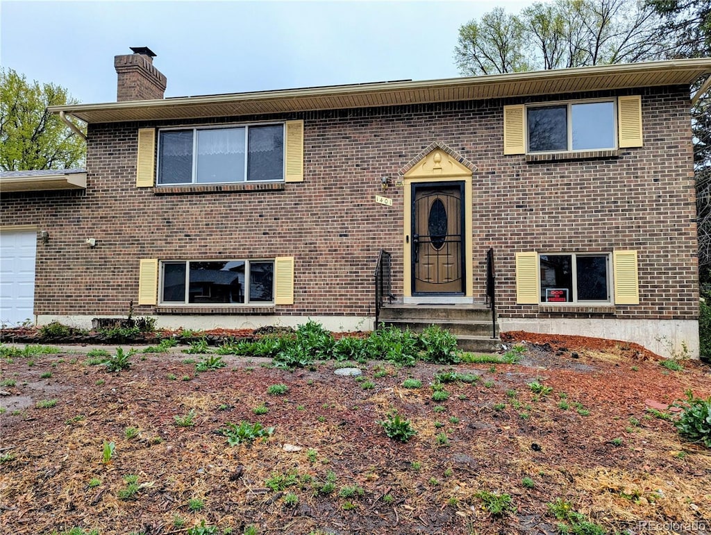 bi-level home with a chimney and brick siding