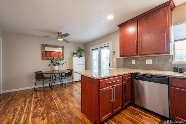 kitchen with dark wood-style flooring, tasteful backsplash, stainless steel dishwasher, freestanding refrigerator, and a peninsula