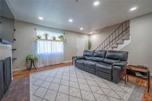 living area with recessed lighting, a fireplace, wood finished floors, baseboards, and stairs