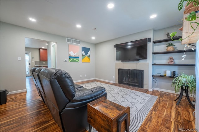 living area with recessed lighting, visible vents, wood finished floors, a tile fireplace, and baseboards