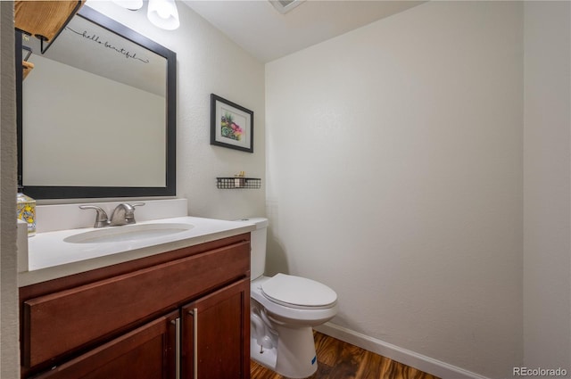 bathroom with baseboards, vanity, toilet, and wood finished floors