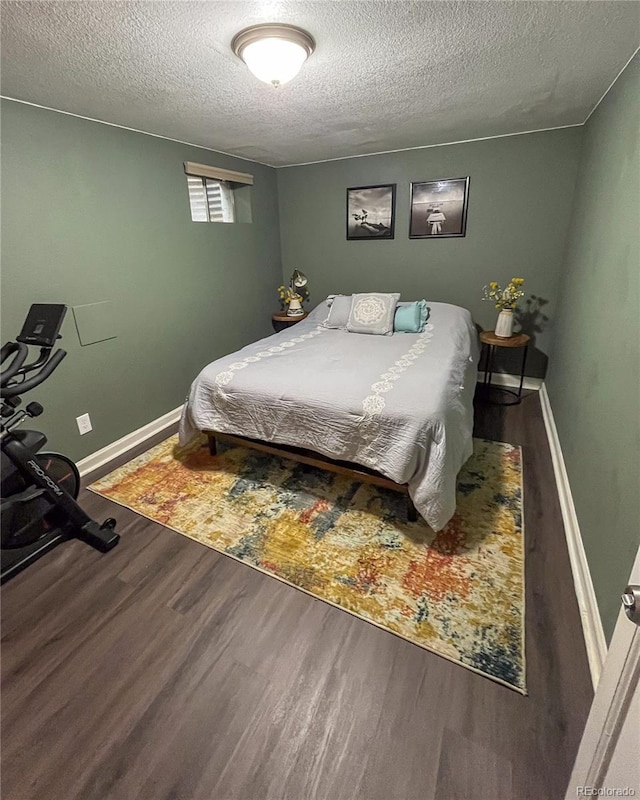 bedroom with a textured ceiling, baseboards, and wood finished floors