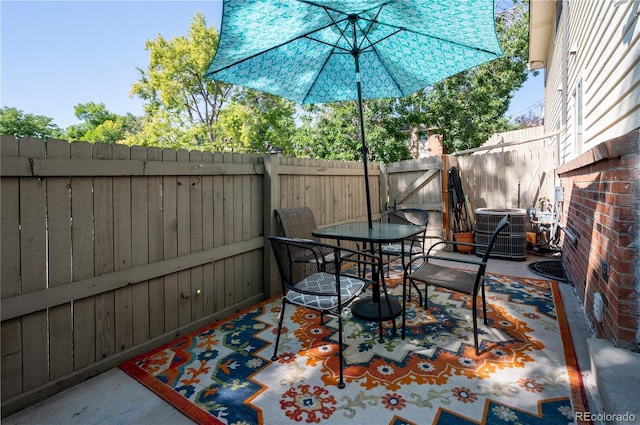 view of patio / terrace with central air condition unit, a fenced backyard, a gate, and outdoor dining area