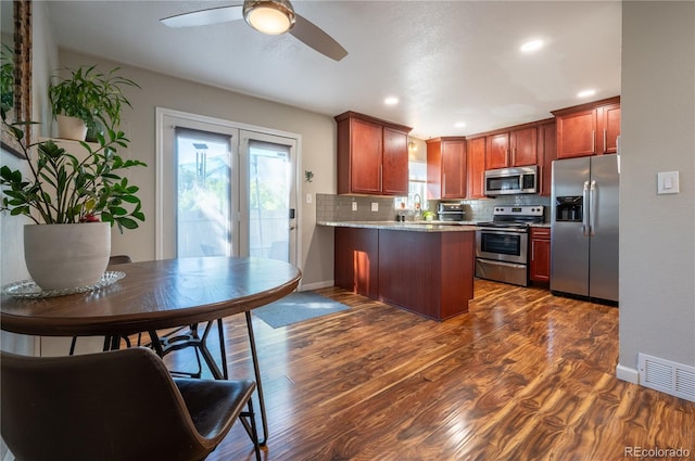 kitchen with visible vents, decorative backsplash, stainless steel appliances, and dark wood-style flooring