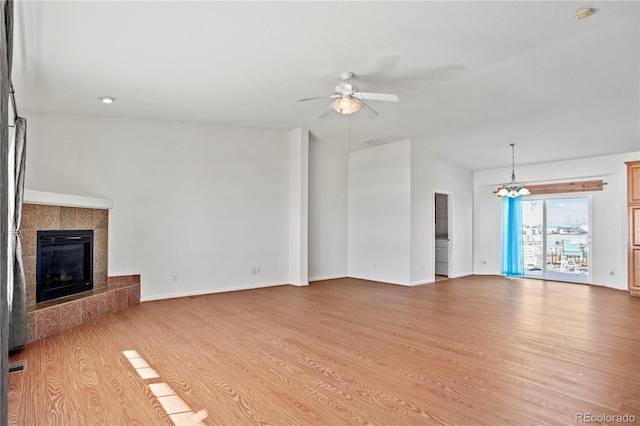 51 W 6th Pl, Byers, CO 80103 - unfurnished living room with a ceiling fan, light wood-type flooring, a tiled fireplace, and a chandelier