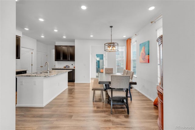 dining space featuring an inviting chandelier, sink, and light wood-type flooring