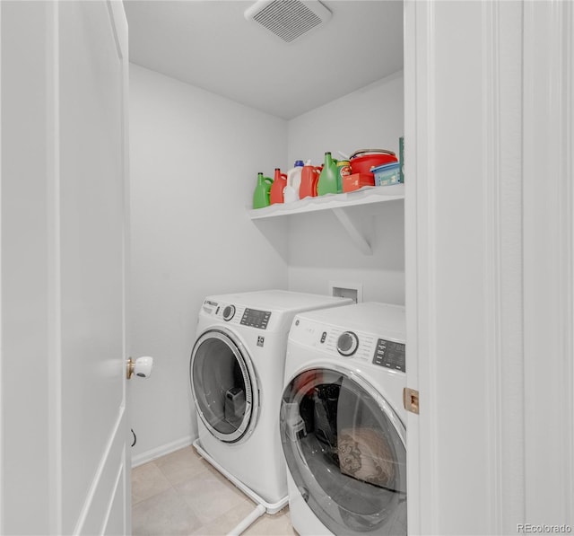 clothes washing area featuring light tile patterned floors and washer and clothes dryer