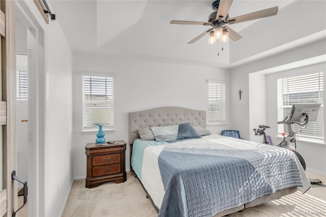 bedroom with light carpet, a tray ceiling, a barn door, and ceiling fan