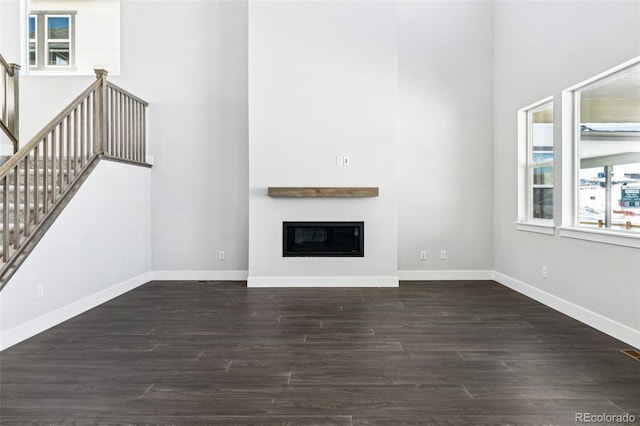 unfurnished living room featuring dark hardwood / wood-style floors and a towering ceiling