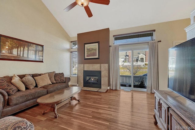 living room featuring plenty of natural light, a tile fireplace, high vaulted ceiling, and wood finished floors