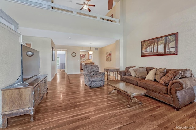 living room featuring a ceiling fan, wood finished floors, visible vents, and baseboards