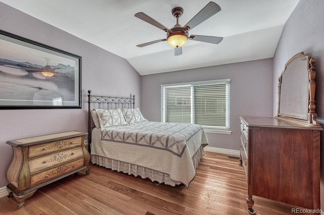 bedroom featuring lofted ceiling, wood finished floors, baseboards, and ceiling fan