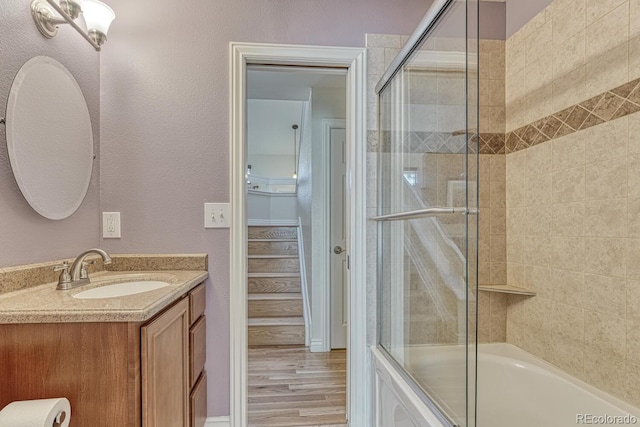 full bath with shower / bath combination with glass door, wood finished floors, and vanity