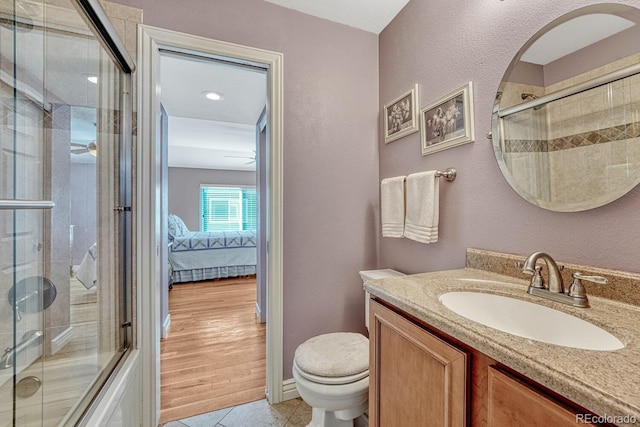 ensuite bathroom featuring tiled shower, toilet, vanity, and tile patterned flooring