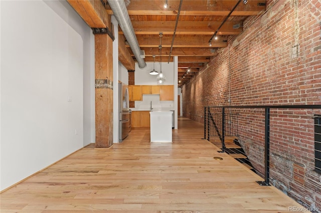 basement featuring light hardwood / wood-style floors, wood ceiling, brick wall, and stainless steel refrigerator