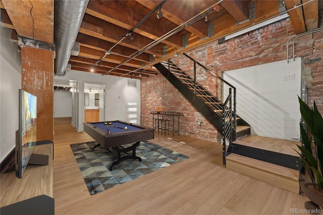 recreation room with hardwood / wood-style flooring, brick wall, and billiards