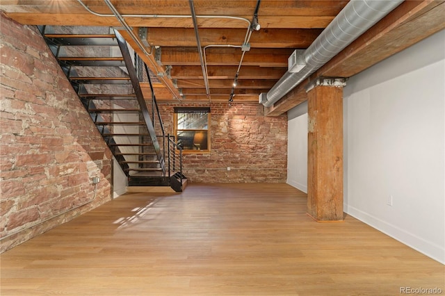 basement with light wood-type flooring and brick wall