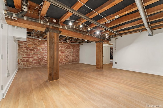 basement with hardwood / wood-style flooring and brick wall