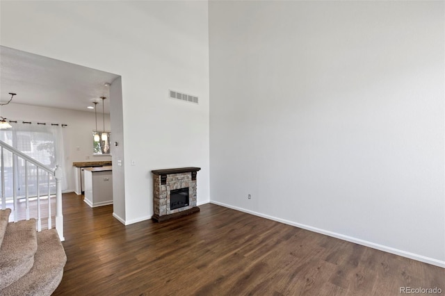 4807 S Killarney Ct, Aurora, CO 80015 - unfurnished living room with dark wood finished floors, stairs, and a stone fireplace